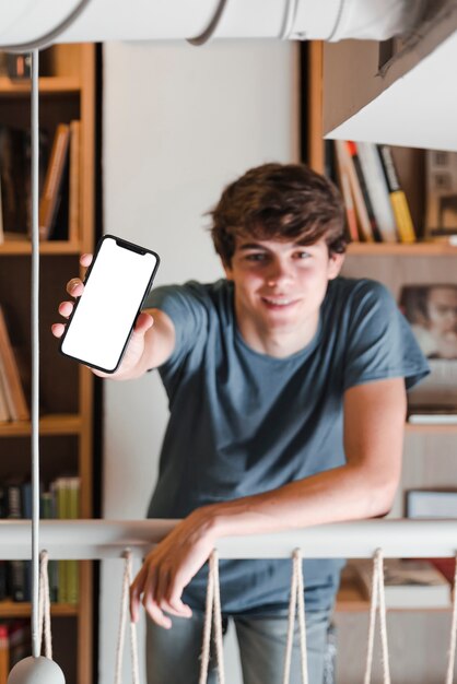 Adolescente che mostra smartphone in biblioteca