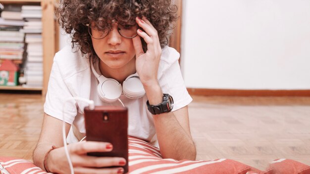 Adolescente che utilizza smartphone sul pavimento