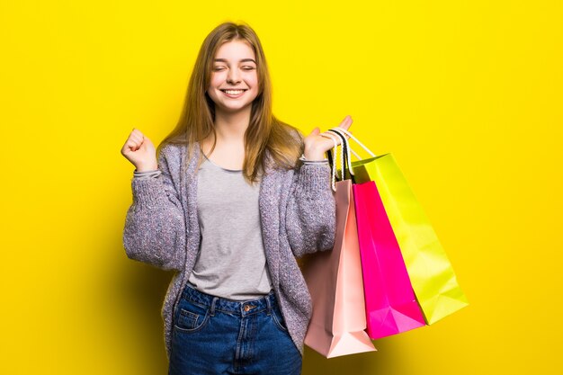 Adolescente eccitato abbastanza felice con i sacchetti della spesa di colore