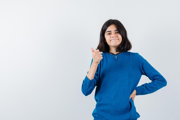 Adolescente felice che tiene un buon segno della mano su fondo bianco