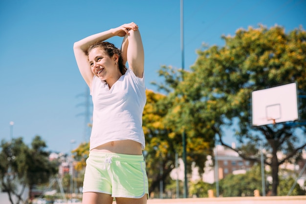 Adolescente femminile contentissimo sportivo che si scalda all&#39;aperto