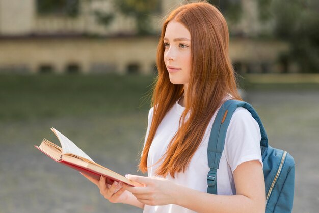 Adolescente grazioso che cammina attraverso il campus universitario