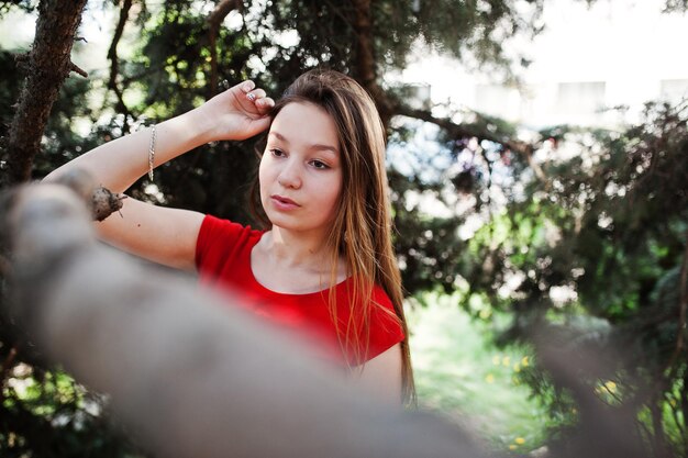 Adolescente in vestito rosso poste all'aperto in una giornata di sole