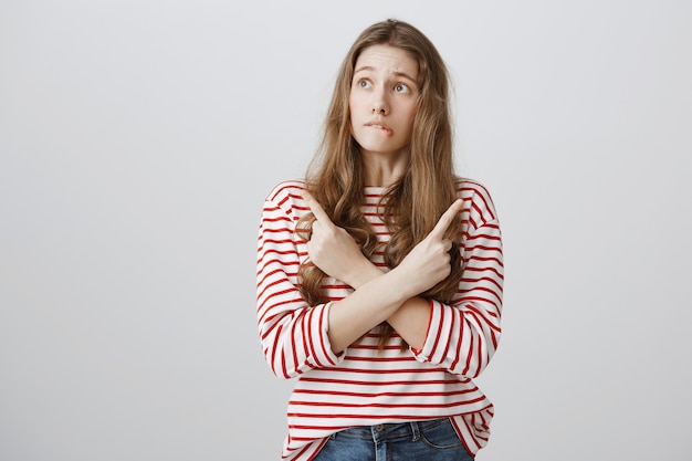 Adolescente indeciso e perplesso che punta il dito di lato, guardando a sinistra cercando di fare una scelta