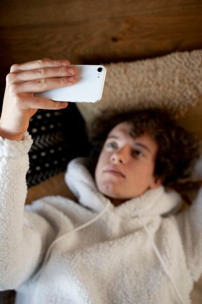 Adolescente sdraiato a letto e guardando il suo smartphone