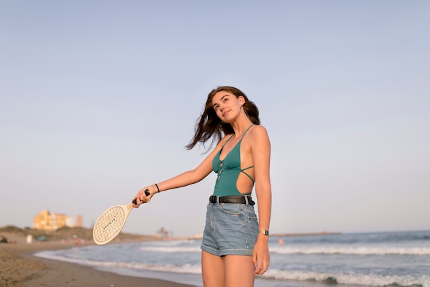 Adolescente sorridente che gioca con la racchetta alla spiaggia