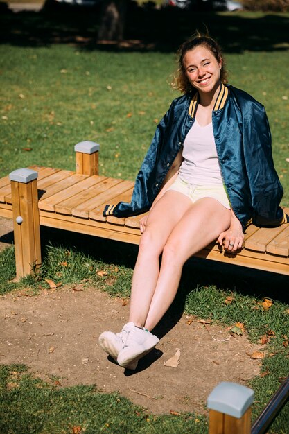 Adolescente sorridente che si siede al parco
