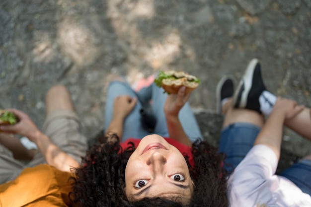 Adolescenti all'aperto insieme gustando un hamburger