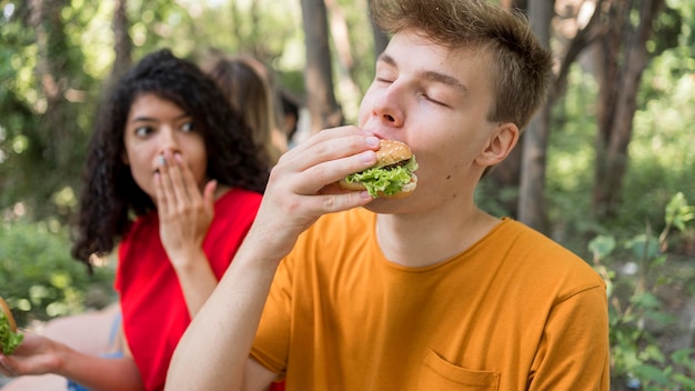 Adolescenti che godono di un hamburger all'aperto