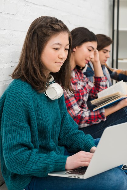 Adolescenti che utilizzano computer portatile e lettura