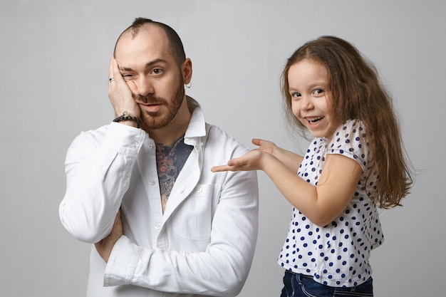 Adorabile bambina con i capelli scuri sciolti che ride, che guarda l'obbiettivo con un sorriso gioioso, divertendosi in studio