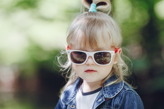 Adorabile bambina in posa con occhiali da sole