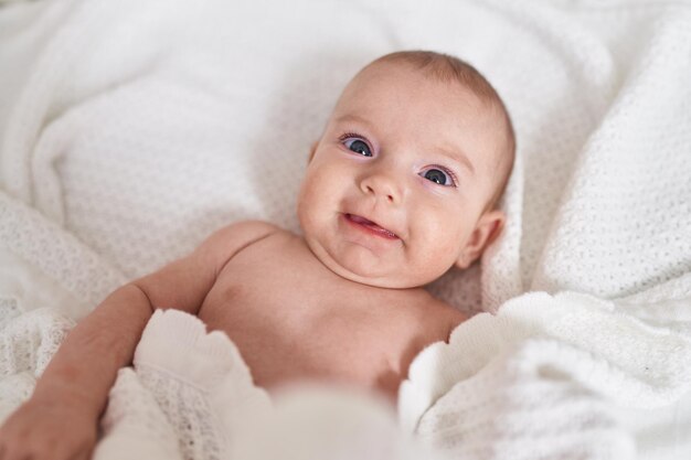 Adorabile bambino caucasico sorridente fiducioso sdraiato sul letto in camera da letto