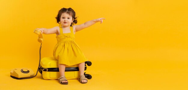 Adorabile bambino in posa con telefono e bagagli