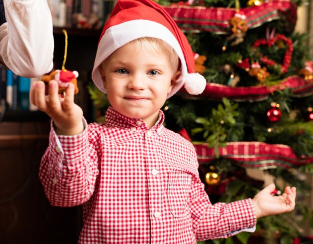 Adorabile bambino in possesso di un ornamento di Natale