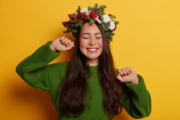 Adorabile giovane donna sorride piacevolmente indossando una festosa corona sulla testa