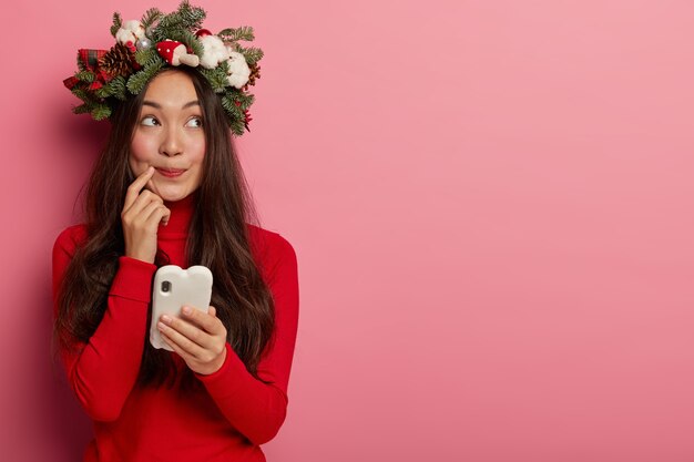 Adorabile giovane donna sorride piacevolmente indossando una festosa corona sulla testa