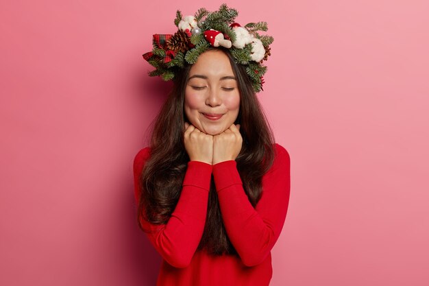 Adorabile giovane donna sorride piacevolmente indossando una festosa corona sulla testa