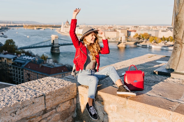 Adorabile giovane modella con capelli castano chiaro che esprime emozioni felici, viaggiando in Europa