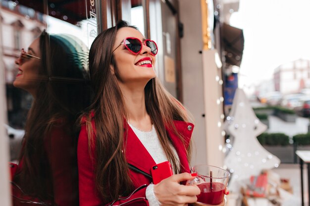 Adorabile modello femminile dai capelli scuri che gode della bevanda preferita nel fine settimana