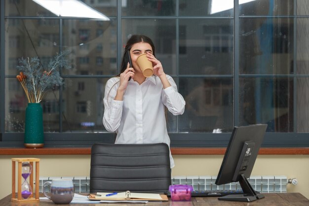 Adorabile ragazza che beve caffè e parla al telefono