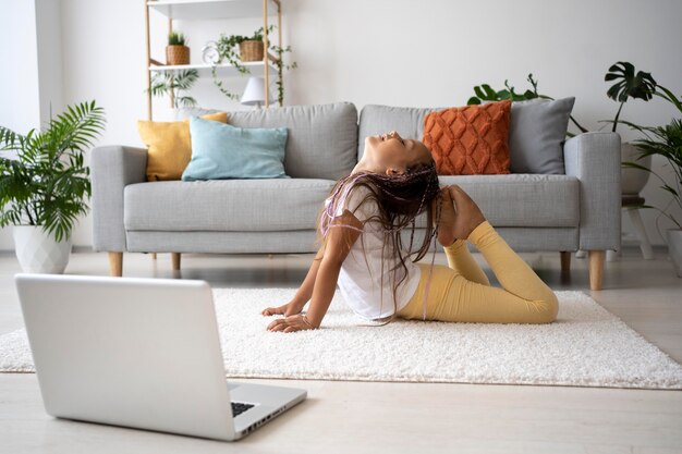 Adorabile ragazza che fa yoga a casa