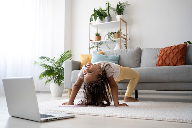 Adorabile ragazza che fa yoga a casa