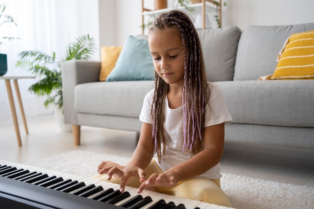 Adorabile ragazza che suona il pianoforte a casa