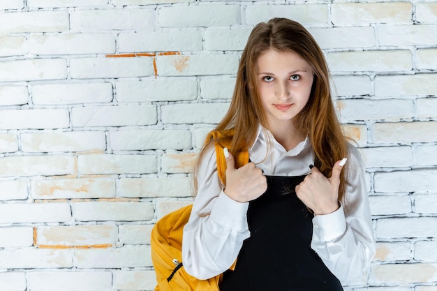 Adorabile studentessa si erge su sfondo bianco e gesto pollice in su