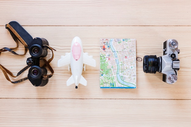 Aereo; binocolo; mappa e macchina fotografica sullo sfondo in legno