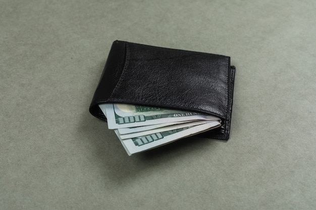 Affare e concetto finanziario con i dollari in portafoglio sulla disposizione del piano della superficie di gray.
