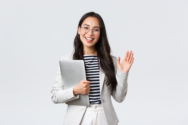 Affari, finanza e occupazione, concetto di imprenditrici di successo. Gestore di ufficio sorridente amichevole che saluta il nuovo collega. La donna d'affari accoglie i clienti con un gesto della mano, tiene il laptop