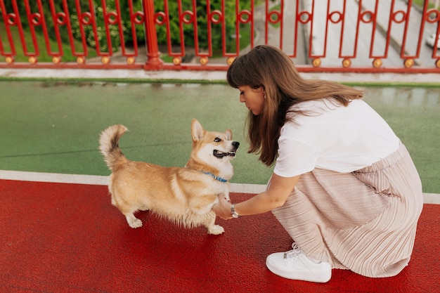 Affascinante donna adorabile che gioca con il suo cagnolino in città Ritratto all'aperto di ragazza con cane