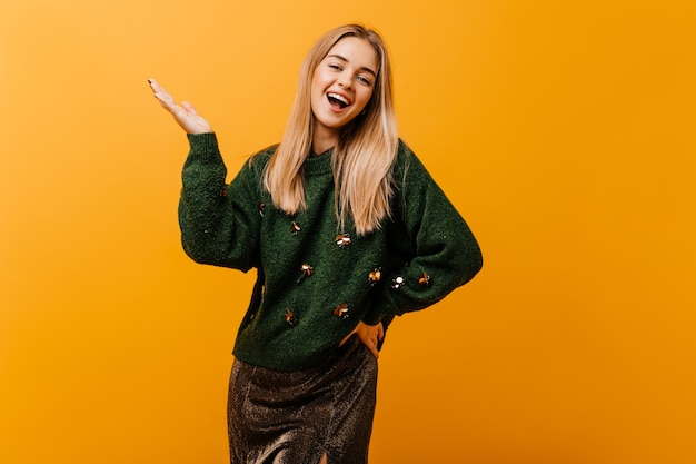 Affascinante donna bianca in maglione oversize che esprime emozioni sincere. Ritratto dell'interno della donna amabile con un bel sorriso.