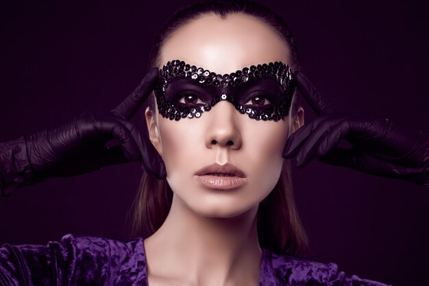 Affascinante donna bruna elegante in maschera di paillettes e guanti