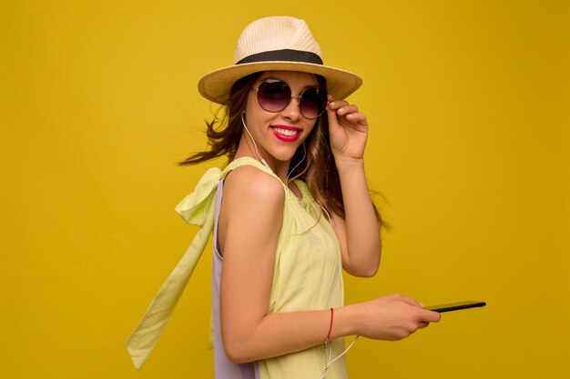 Affascinante donna elegante con gli occhiali e cappello con lo smartphone
