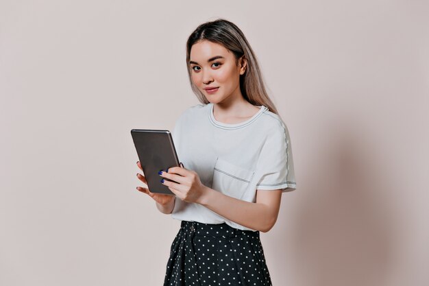 Affascinante donna in t-shirt bianca che tiene tablet computer