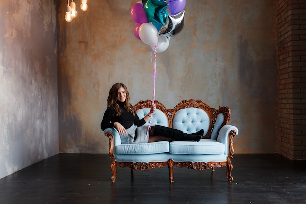 Affascinante giovane donna bruna in possesso di un grande fascio di palloncini di elio