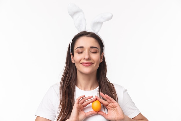 affascinante giovane donna in orecchie di coniglio tenendo un uovo colorato