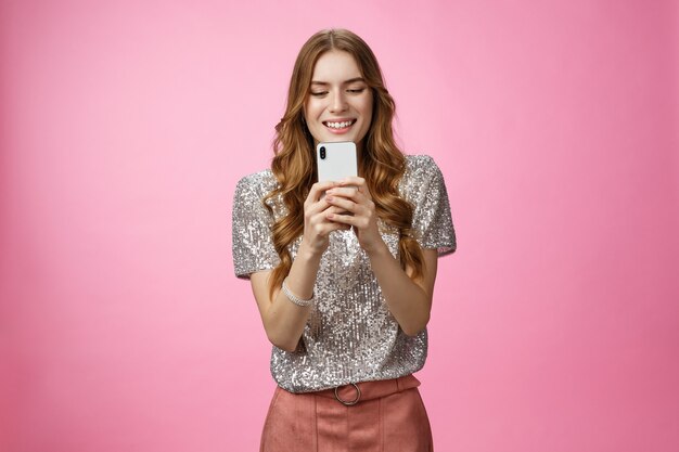 Affascinante glamour socievole elegante femmina caucasica che utilizza lo smartphone alla ricerca dello schermo del telefono cellulare...