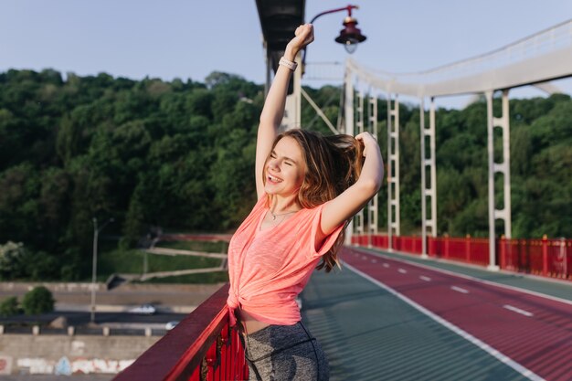 Affascinante ragazza bianca che si estende e che ride. Ritratto di donna allegra ballando allo stadio.