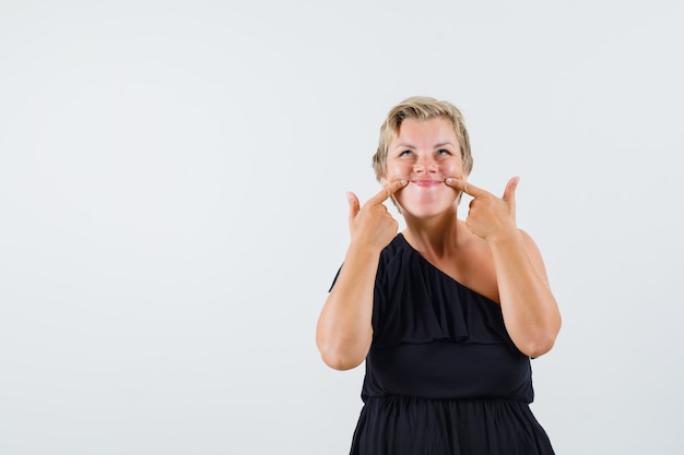 Affascinante signora che fa sorriso falso in vista frontale camicetta nera.