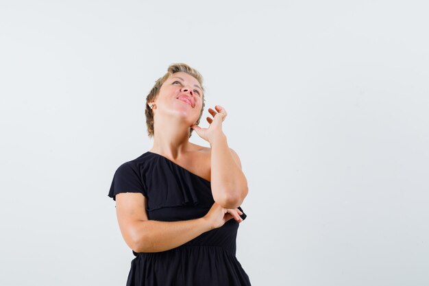 Affascinante signora in posa come fare una telefonata in camicetta nera e sembra felice. vista frontale.