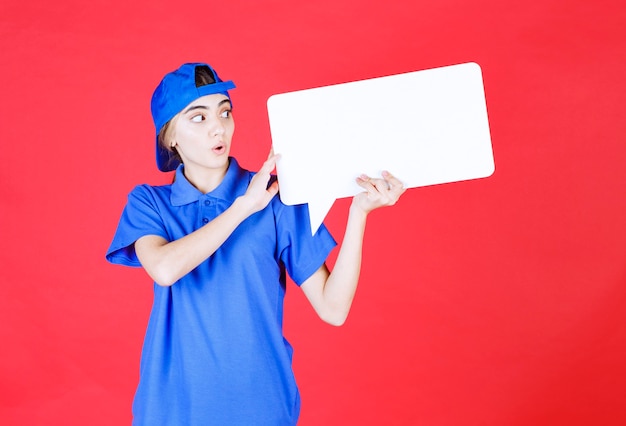 Agente di servizio femminile in uniforme blu che tiene un banco informazioni di rettangolo.