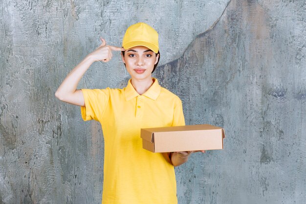 Agente di servizio femminile in uniforme gialla che tiene una scatola di cartone e sembra confuso e premuroso.