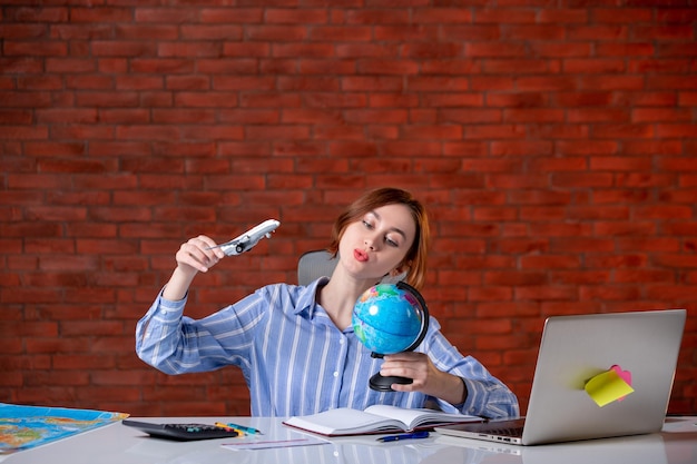 Agente di viaggio di vista frontale seduto dietro il suo posto di lavoro osservando il piccolo servizio di assistenza al chiuso dell'agenzia dell'assistente della mappa del mondo