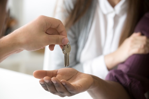 Agente immobiliare che fornisce le chiavi africane del cliente, coppia che compra nuova casa, primo piano