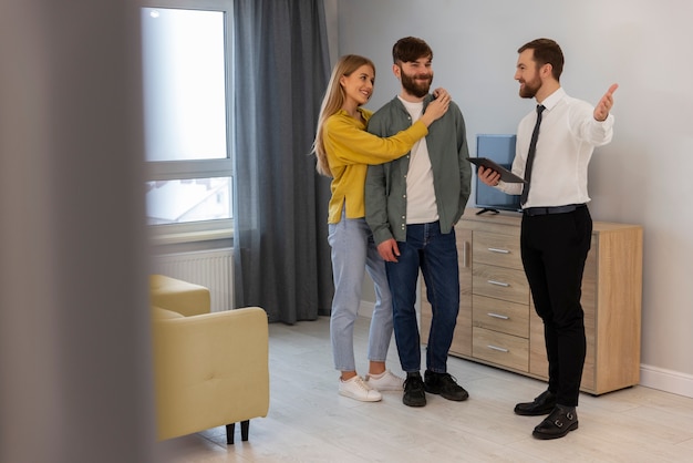 Agente immobiliare maschio che fa affari e mostra casa a potenziali coppie di acquirenti