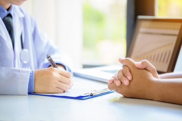 Aggiusti il paziente consultantesi dell&#39;uomo mentre compilano un modulo di domanda allo scrittorio in ospedale.