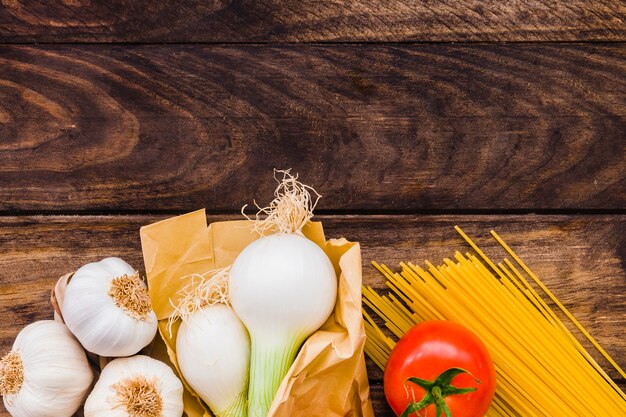 Aglio e cipolla vicino a pomodoro e spaghetti